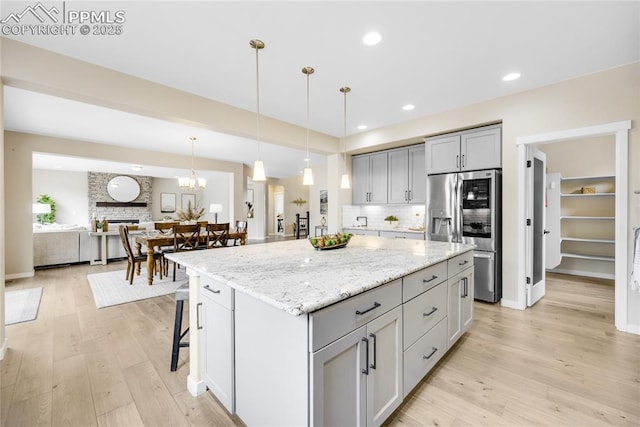 kitchen featuring decorative backsplash, gray cabinetry, light wood finished floors, and stainless steel fridge with ice dispenser