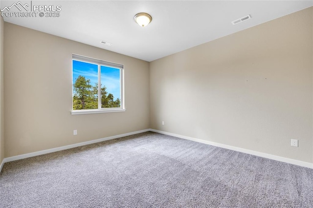 empty room with carpet, visible vents, and baseboards