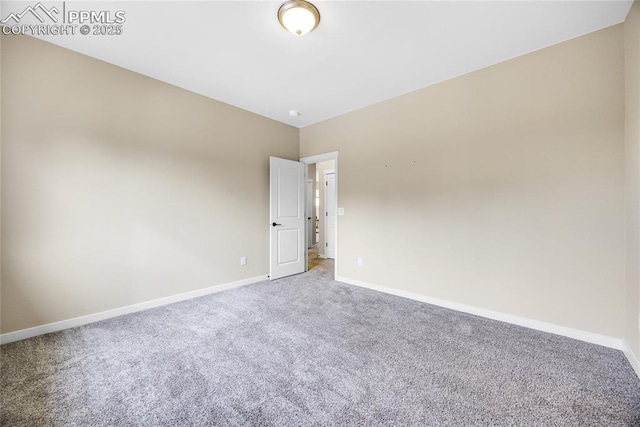 carpeted empty room featuring baseboards