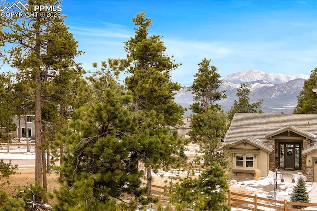 exterior space with stone siding, a tile roof, fence, a mountain view, and stucco siding