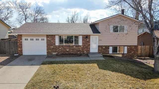 split level home featuring a front yard, a garage, fence, and brick siding