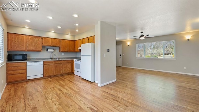 kitchen with light wood finished floors, white appliances, brown cabinetry, light countertops, and baseboards