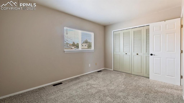 unfurnished bedroom featuring a closet, carpet flooring, visible vents, and baseboards