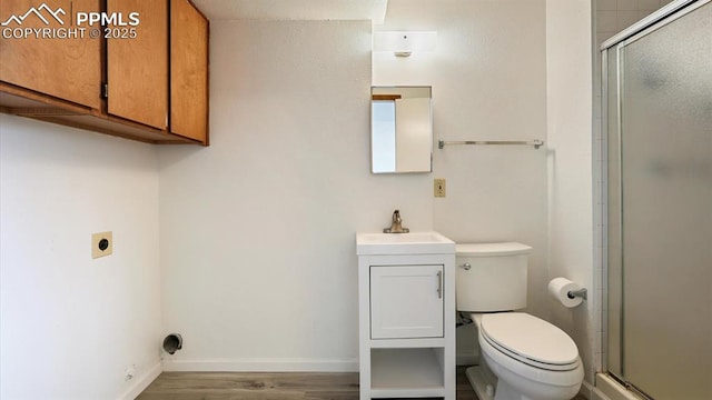 bathroom with a stall shower, toilet, vanity, and baseboards