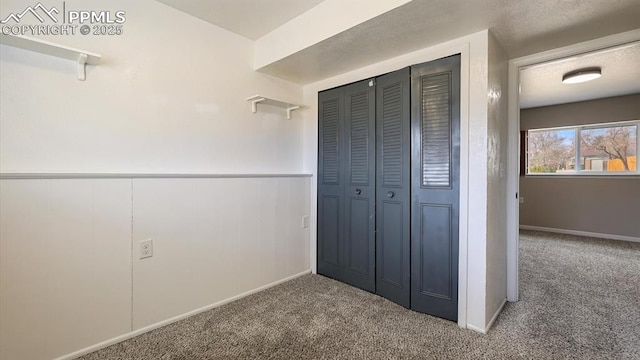 unfurnished bedroom with a closet, wainscoting, and carpet flooring