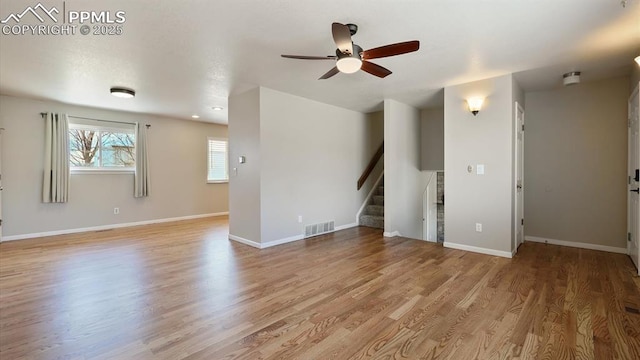 unfurnished living room featuring visible vents, baseboards, light wood-style flooring, and stairs