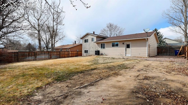 rear view of house with cooling unit, a lawn, and a fenced backyard