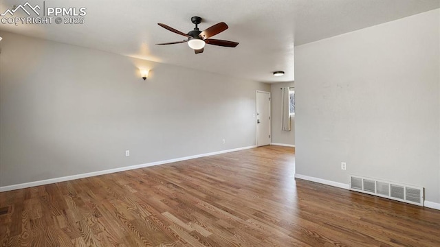 empty room with ceiling fan, visible vents, baseboards, and wood finished floors