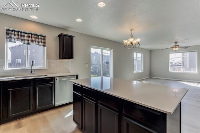 kitchen with light wood finished floors, backsplash, dishwasher, light countertops, and a sink