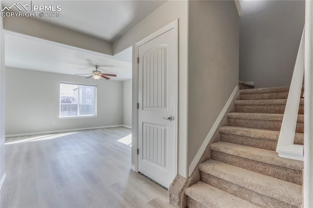 stairs featuring ceiling fan, baseboards, and wood finished floors