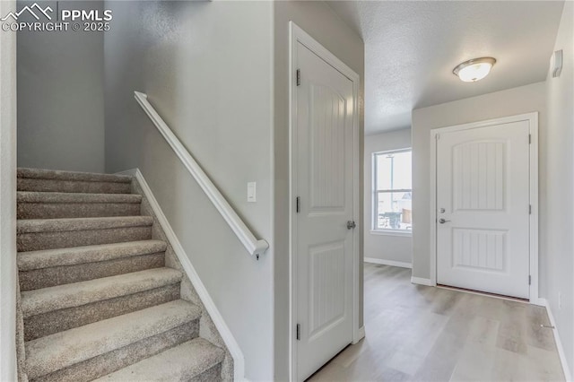 stairs featuring wood finished floors, baseboards, and a textured ceiling