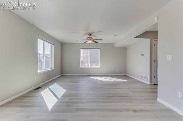 empty room featuring ceiling fan, baseboards, visible vents, and light wood-type flooring