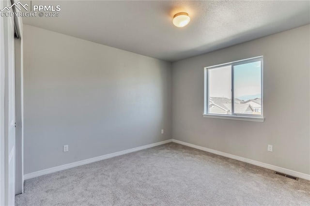 spare room with visible vents, a textured ceiling, baseboards, and carpet floors