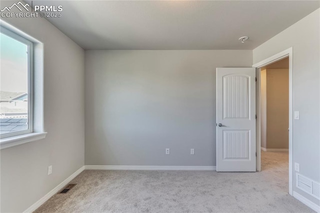 carpeted spare room with visible vents and baseboards