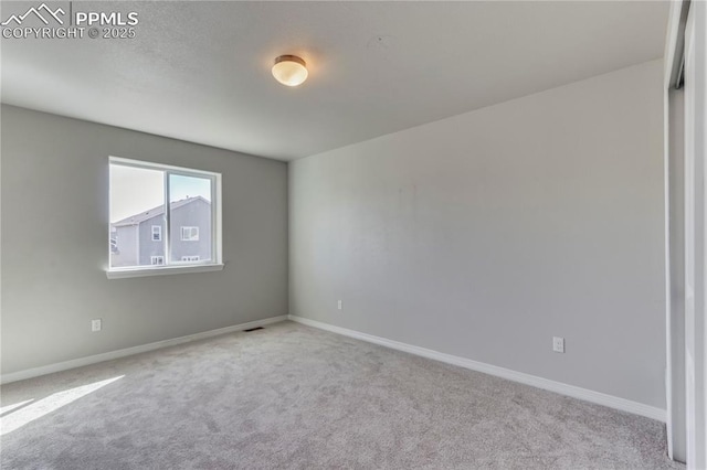 empty room featuring carpet flooring, visible vents, and baseboards