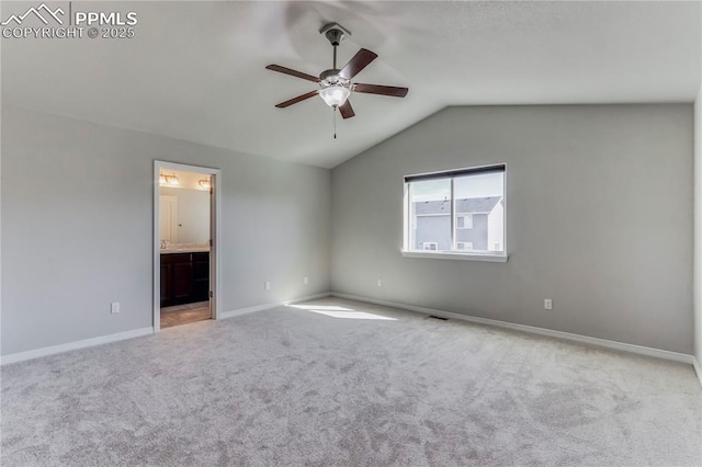 interior space with visible vents, baseboards, vaulted ceiling, carpet flooring, and connected bathroom