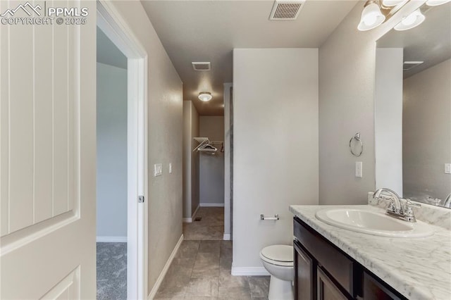 bathroom with visible vents, baseboards, toilet, and vanity