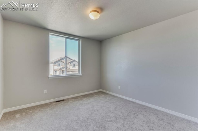 empty room featuring visible vents, carpet flooring, a textured ceiling, and baseboards