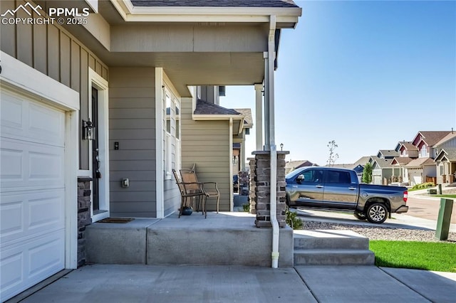 view of patio featuring driveway, covered porch, a garage, and a residential view