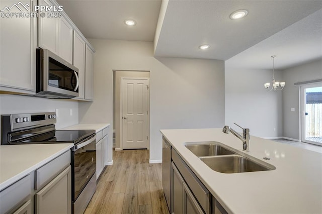 kitchen with appliances with stainless steel finishes, light wood-style floors, light countertops, and a sink