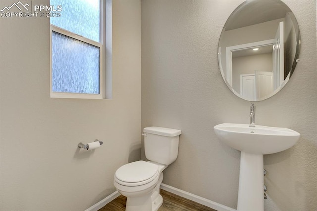 half bathroom featuring toilet, baseboards, and wood finished floors