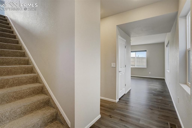 stairway featuring wood finished floors, visible vents, and baseboards