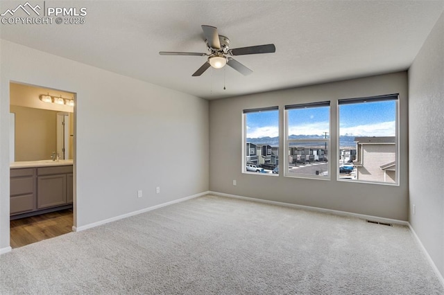 unfurnished bedroom with connected bathroom, a sink, carpet flooring, visible vents, and baseboards