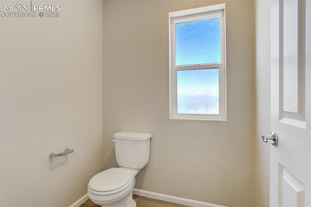 bathroom with wood finished floors, toilet, and baseboards