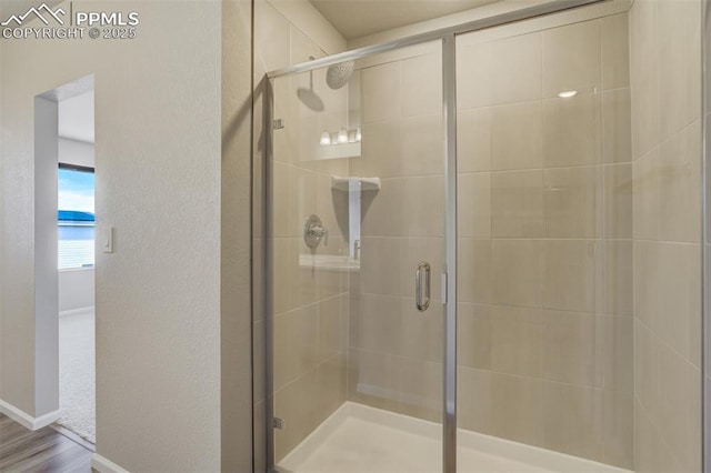 full bath with a stall shower, baseboards, and a textured wall