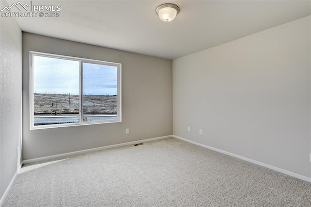 carpeted spare room with visible vents and baseboards