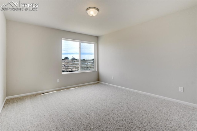 carpeted empty room featuring baseboards