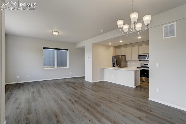 kitchen with stainless steel appliances, light countertops, visible vents, open floor plan, and wood finished floors