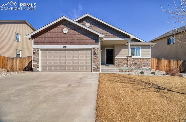 craftsman inspired home featuring a garage, stone siding, fence, and concrete driveway