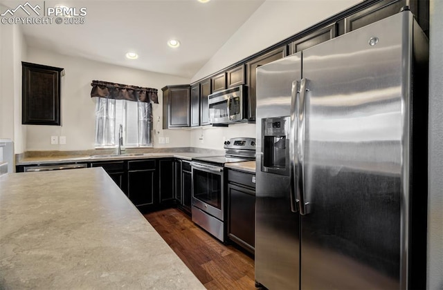 kitchen featuring stainless steel appliances, lofted ceiling, light countertops, dark wood-type flooring, and a sink