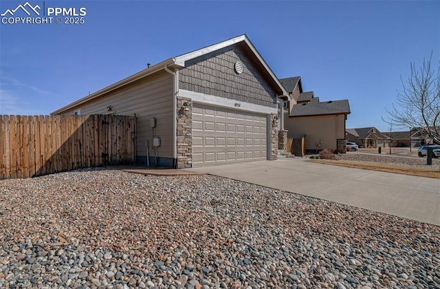 view of property exterior featuring a garage, fence, driveway, stone siding, and a residential view