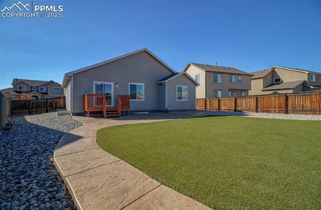 back of property with a fenced backyard, a yard, a wooden deck, and a patio