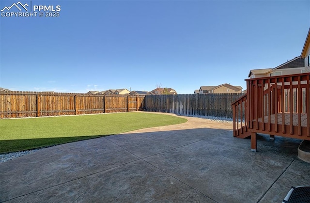 view of yard with a deck, a patio, and a fenced backyard