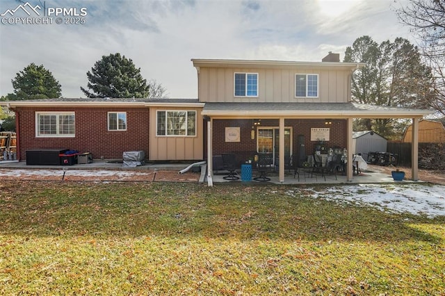 rear view of property featuring board and batten siding, brick siding, a patio, and a shed