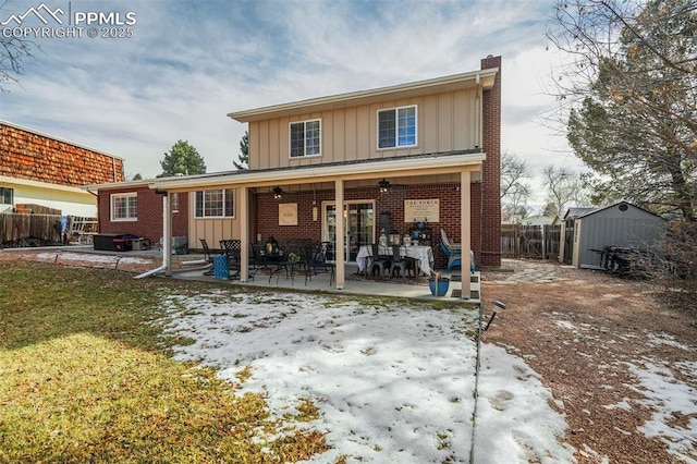 rear view of property featuring board and batten siding, a patio area, fence, and brick siding