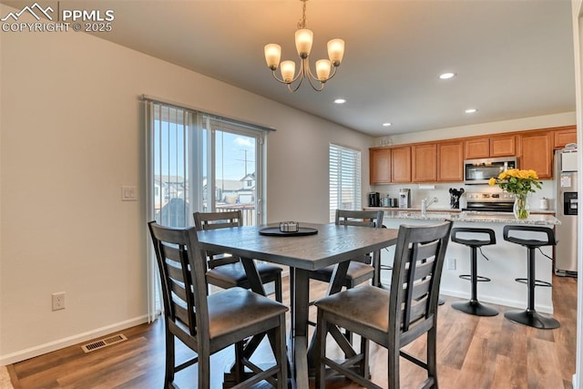 dining area featuring an inviting chandelier, visible vents, baseboards, and wood finished floors