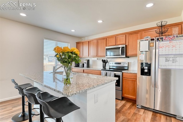 kitchen with appliances with stainless steel finishes, light wood-type flooring, recessed lighting, and a center island