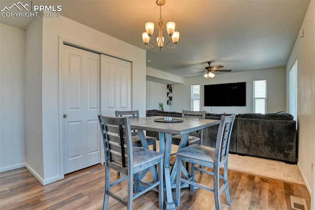 dining room featuring visible vents, baseboards, wood finished floors, and ceiling fan with notable chandelier