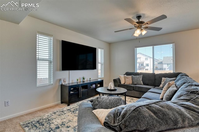 living area featuring carpet floors, a ceiling fan, baseboards, and a wealth of natural light