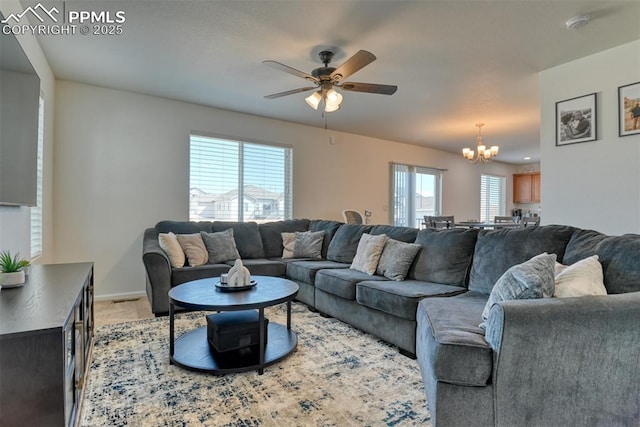 living room with light carpet, baseboards, and ceiling fan with notable chandelier