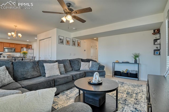 living area with light carpet, baseboards, and ceiling fan with notable chandelier