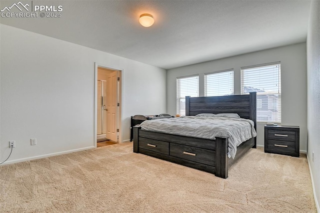 bedroom featuring light colored carpet, ensuite bath, baseboards, and a textured ceiling