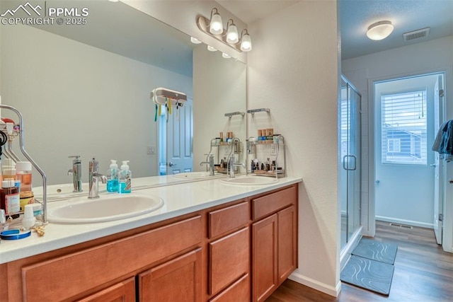 bathroom with double vanity, a stall shower, a sink, and visible vents