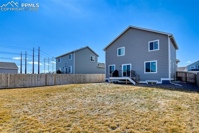 rear view of property with a fenced backyard and a yard