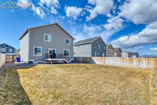 back of house featuring a deck, a yard, and a fenced backyard