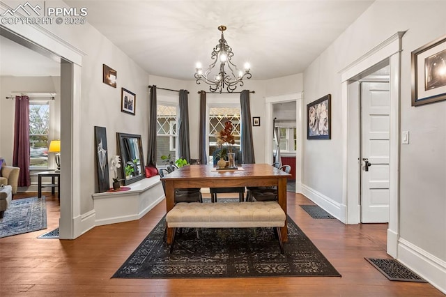 dining room with hardwood / wood-style flooring, baseboards, visible vents, and a chandelier